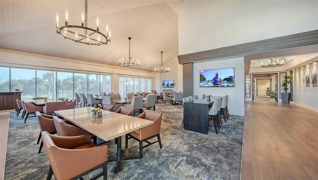dining space featuring a chandelier, high vaulted ceiling, healthy amount of natural light, baseboards, and wood finished floors