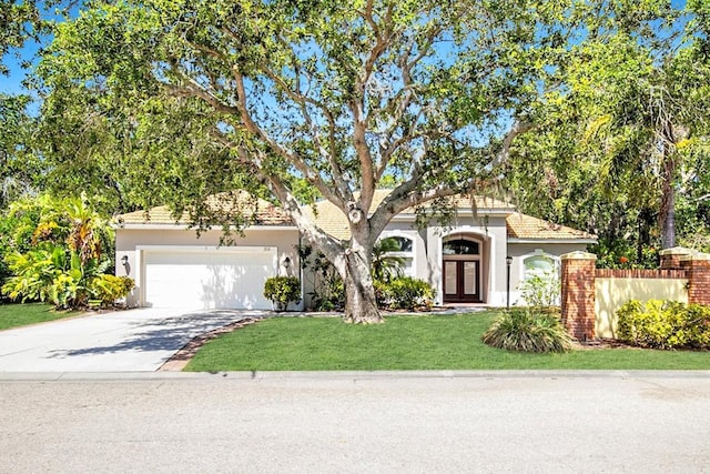 view of front of house with a garage, a front lawn, stucco siding, french doors, and driveway