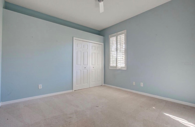 unfurnished bedroom featuring carpet floors, baseboards, and a closet