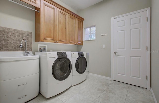 laundry area featuring cabinet space, separate washer and dryer, baseboards, and light tile patterned floors