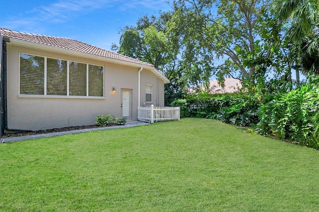exterior space featuring a lawn, fence, and stucco siding