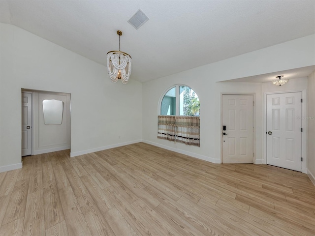 245 Woodingham Trl, Venice, FL 34292 - spare room featuring a chandelier, light wood-style flooring, vaulted ceiling, and baseboards