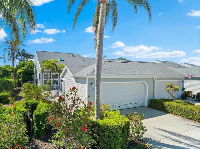 view of front of property featuring concrete driveway, an attached garage, and a shingled roof