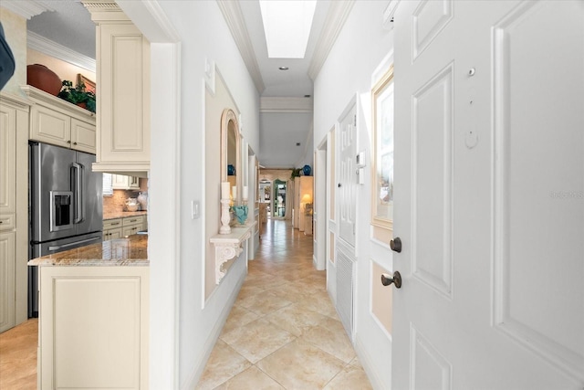 hallway featuring recessed lighting, ornamental molding, light tile patterned floors, and a skylight