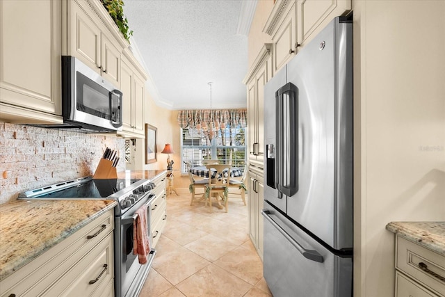 kitchen featuring crown molding, decorative backsplash, cream cabinets, appliances with stainless steel finishes, and light tile patterned floors