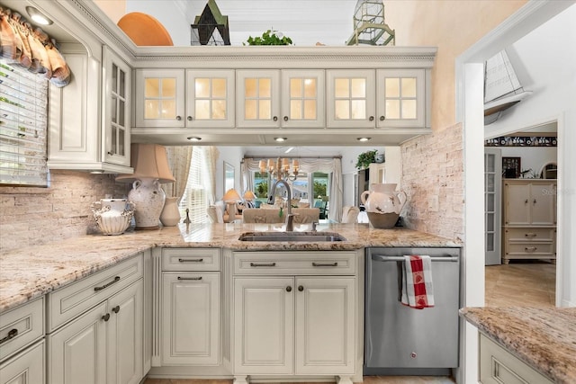 kitchen with light stone counters, tasteful backsplash, a sink, and dishwasher