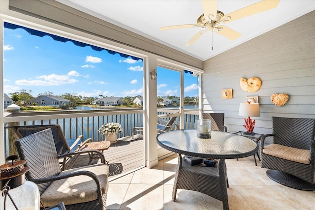 sunroom / solarium featuring a water view, a ceiling fan, and outdoor dining space