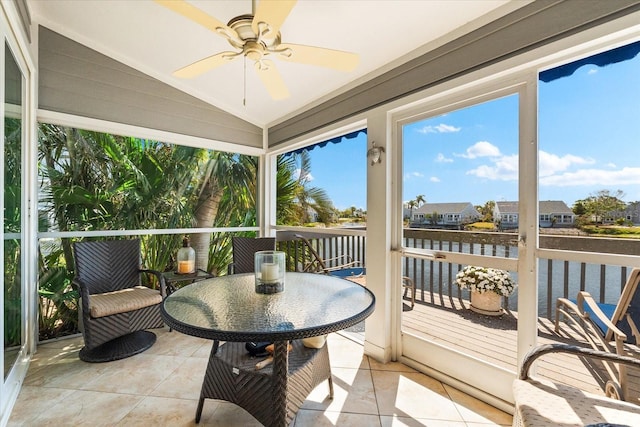 sunroom with a residential view, a ceiling fan, and a water view