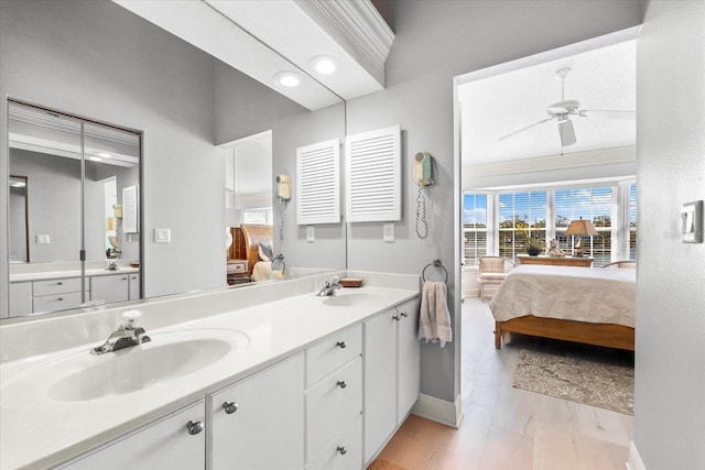 ensuite bathroom with baseboards, a sink, ensuite bath, and double vanity