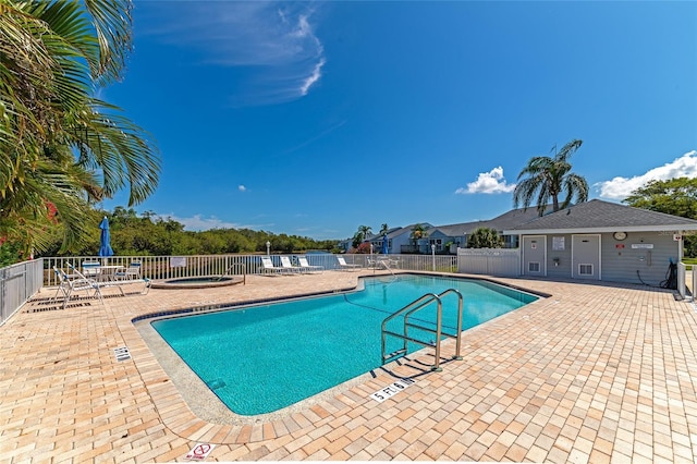 community pool featuring a community hot tub, a patio area, and fence