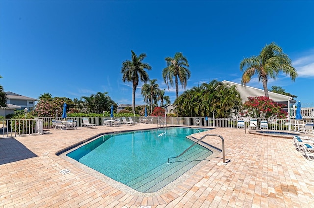 pool featuring fence, a hot tub, and a patio area