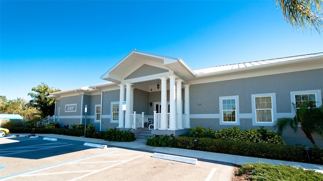 exterior space featuring uncovered parking, stucco siding, a standing seam roof, metal roof, and a porch
