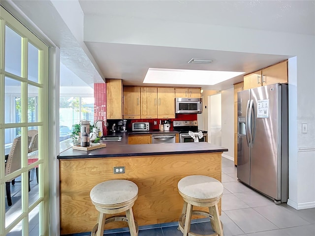 6012 11th Ave W, Bradenton, FL 34209 - kitchen featuring a sink, a peninsula, stainless steel appliances, light tile patterned floors, and dark countertops