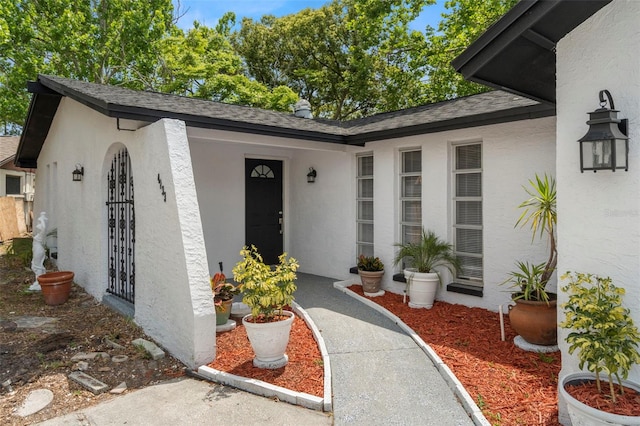 property entrance with roof with shingles and stucco siding