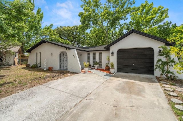 ranch-style home with an attached garage, concrete driveway, and stucco siding