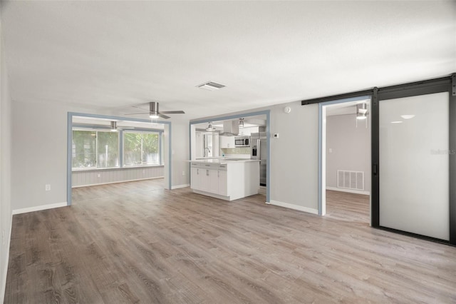 unfurnished living room with ceiling fan, light wood-style floors, and visible vents