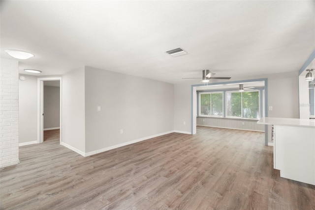 unfurnished room with a ceiling fan, baseboards, light wood-style flooring, and visible vents