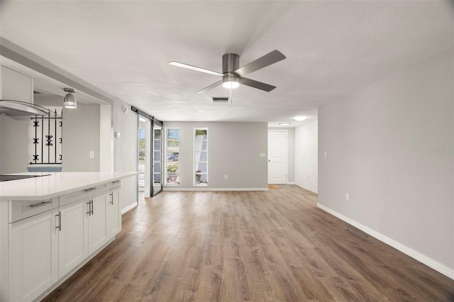 unfurnished living room featuring light wood-type flooring, visible vents, and baseboards