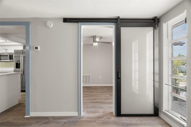 interior space featuring ceiling fan, light wood-style flooring, visible vents, and a wealth of natural light