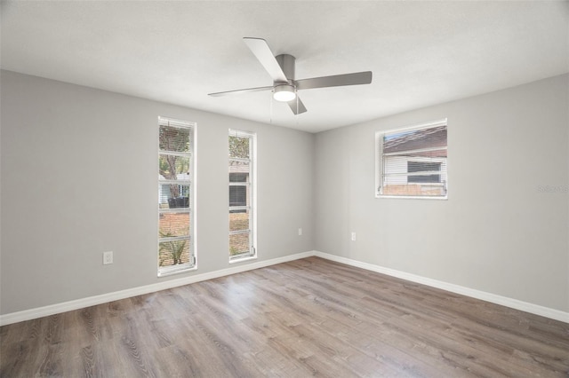 unfurnished room with plenty of natural light, wood finished floors, and baseboards