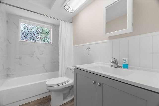 bathroom with toilet, wood finished floors, vanity, shower / bath combination with curtain, and wainscoting