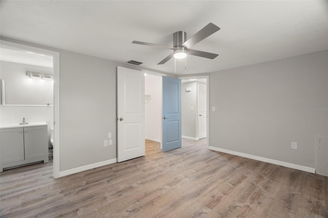 unfurnished bedroom with connected bathroom, light wood-style floors, visible vents, and baseboards