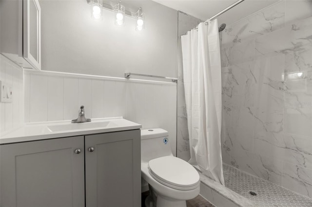 full bath with a wainscoted wall, vanity, toilet, and a shower stall