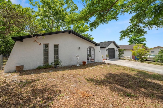 view of front of home with concrete driveway, stucco siding, fence, and a garage