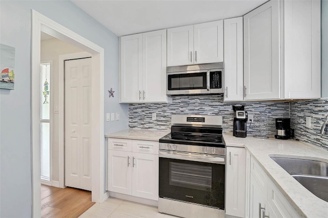 151 Vista Hermosa Cir Unit 31C, Sarasota, FL 34242 - kitchen featuring stainless steel appliances, a sink, decorative backsplash, and white cabinets
