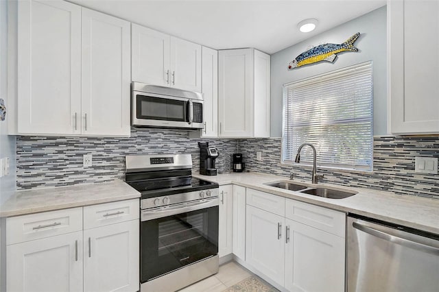 151 Vista Hermosa Cir Unit 31C, Sarasota, FL 34242 - kitchen with appliances with stainless steel finishes, a sink, white cabinets, light tile patterned flooring, and backsplash