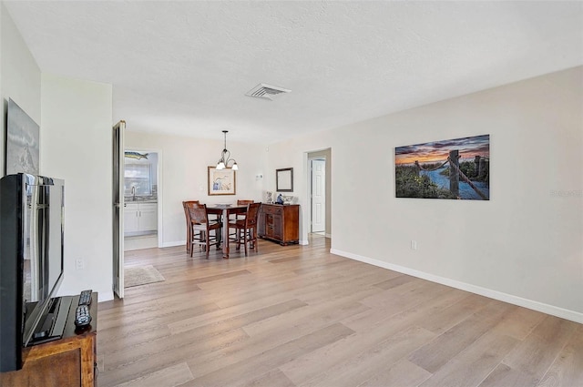 151 Vista Hermosa Cir Unit 31C, Sarasota, FL 34242 - living room featuring light wood-style flooring, baseboards, and a chandelier