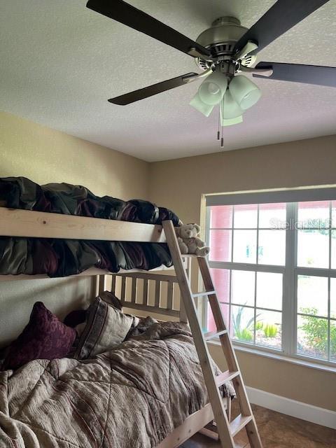 7286 Mineola Rd, Englewood, FL 34224 - bedroom featuring a textured ceiling, baseboards, and a ceiling fan