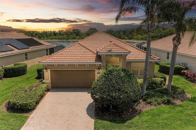 mediterranean / spanish home with stucco siding, an attached garage, a tile roof, and decorative driveway