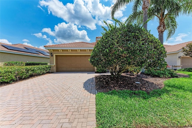 view of front facade featuring stucco siding, a tile roof, decorative driveway, and an attached garage
