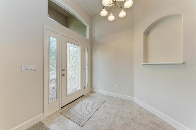 tiled entryway featuring a chandelier and baseboards