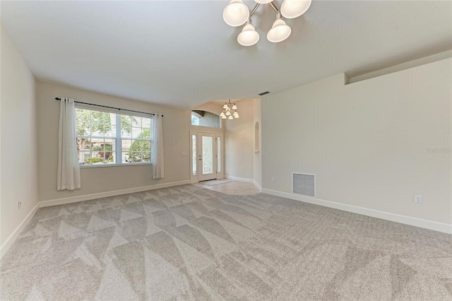 unfurnished room featuring a chandelier, light carpet, and baseboards