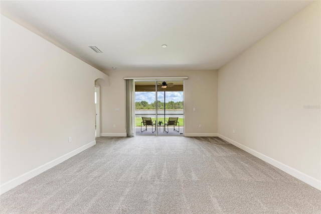carpeted empty room with baseboards and arched walkways