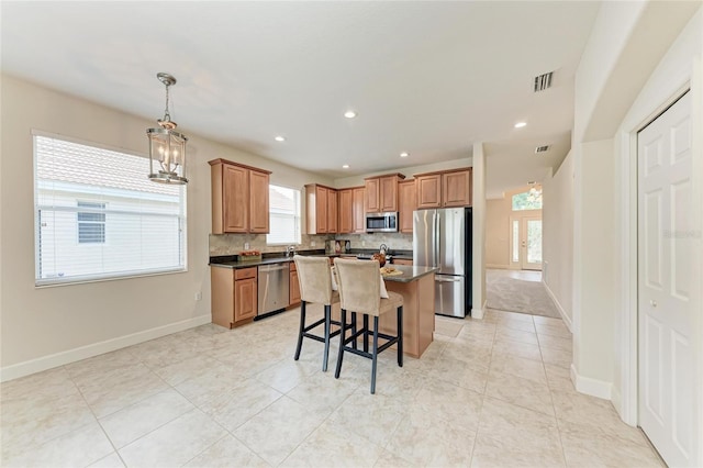 kitchen featuring stainless steel appliances, dark countertops, a breakfast bar, a center island, and recessed lighting