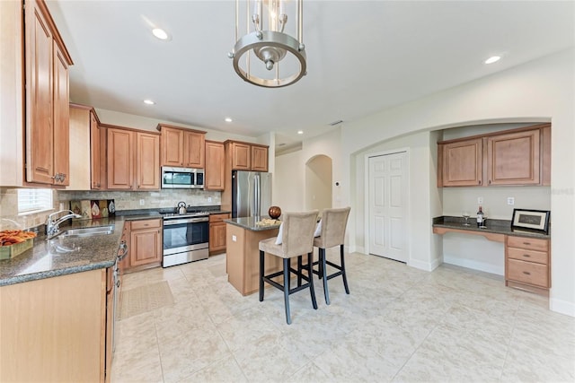 kitchen with stainless steel appliances, a sink, a breakfast bar area, tasteful backsplash, and arched walkways