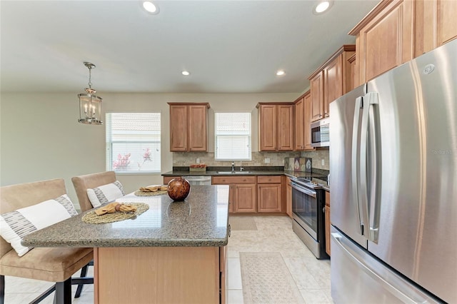 kitchen featuring stainless steel appliances, a sink, decorative backsplash, a kitchen breakfast bar, and recessed lighting