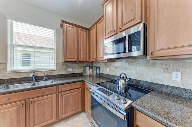 kitchen with appliances with stainless steel finishes, a sink, decorative backsplash, and brown cabinets