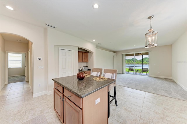 kitchen featuring arched walkways, light tile patterned flooring, a kitchen island, light colored carpet, and recessed lighting