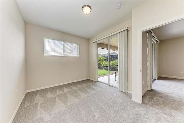 carpeted empty room featuring baseboards and a smoke detector