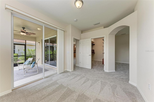 unfurnished room with carpet, arched walkways, baseboards, and ceiling fan