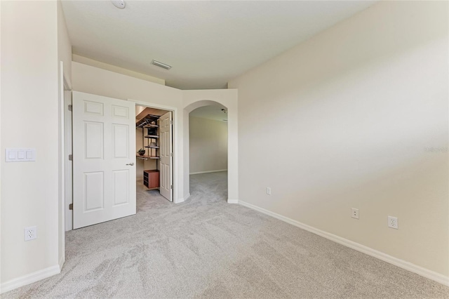 carpeted empty room with arched walkways and baseboards
