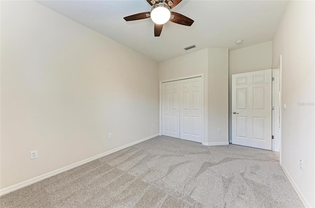 unfurnished bedroom featuring light colored carpet, baseboards, a closet, and ceiling fan
