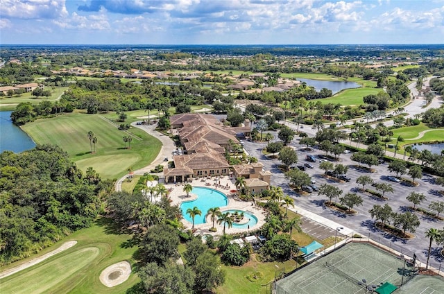bird's eye view of a golf course, a nearby body of water, a pool, and a tree filled landscape