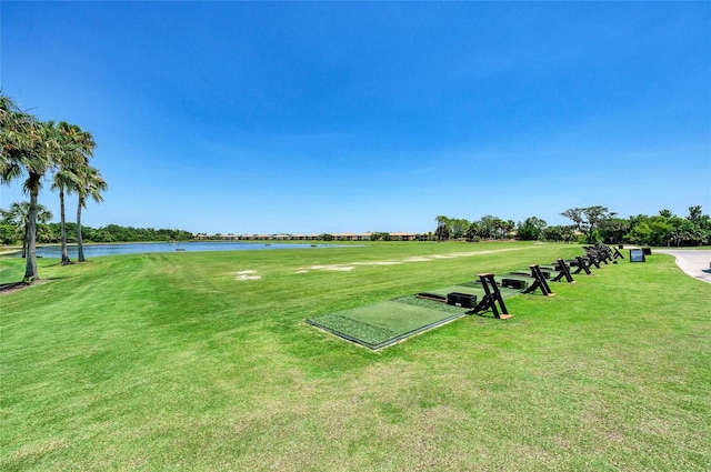 view of home's community with a water view, a lawn, and view of golf course