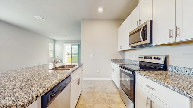 1824 Woodleaf Hammock Ct, Bradenton, FL 34211 - kitchen with appliances with stainless steel finishes, a sink, light stone counters, white cabinetry, and recessed lighting