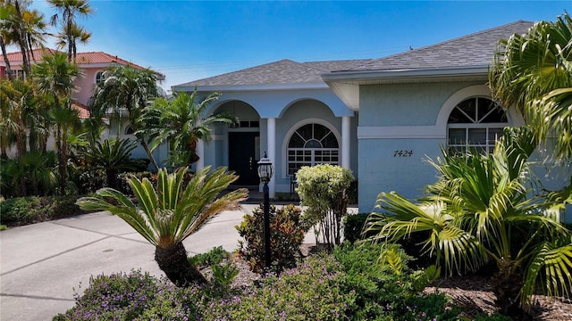 doorway to property with stucco siding and roof with shingles